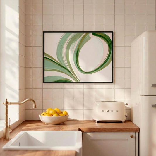 A framed abstract wall art print with flowing green and white brushstrokes hangs on a beige tiled kitchen wall above a wooden countertop with a bowl of lemons, a cream Smeg toaster, and a white sink.