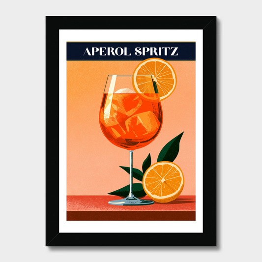 A framed vintage-style poster featuring an illustration of an Aperol Spritz cocktail with orange slices and green leaves on a peach background, with the text 'APEROL SPRITZ' at the top. The print is mounted with a white border and enclosed in a black frame, shown against a light gray background.