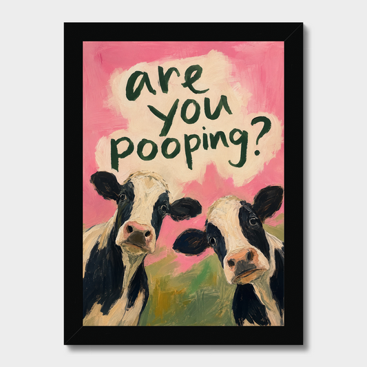 A framed art print featuring two black-and-white cows against a pink background with the text 'are you pooping?' in dark green lettering. The print is enclosed in a black frame and shown against a light gray background.