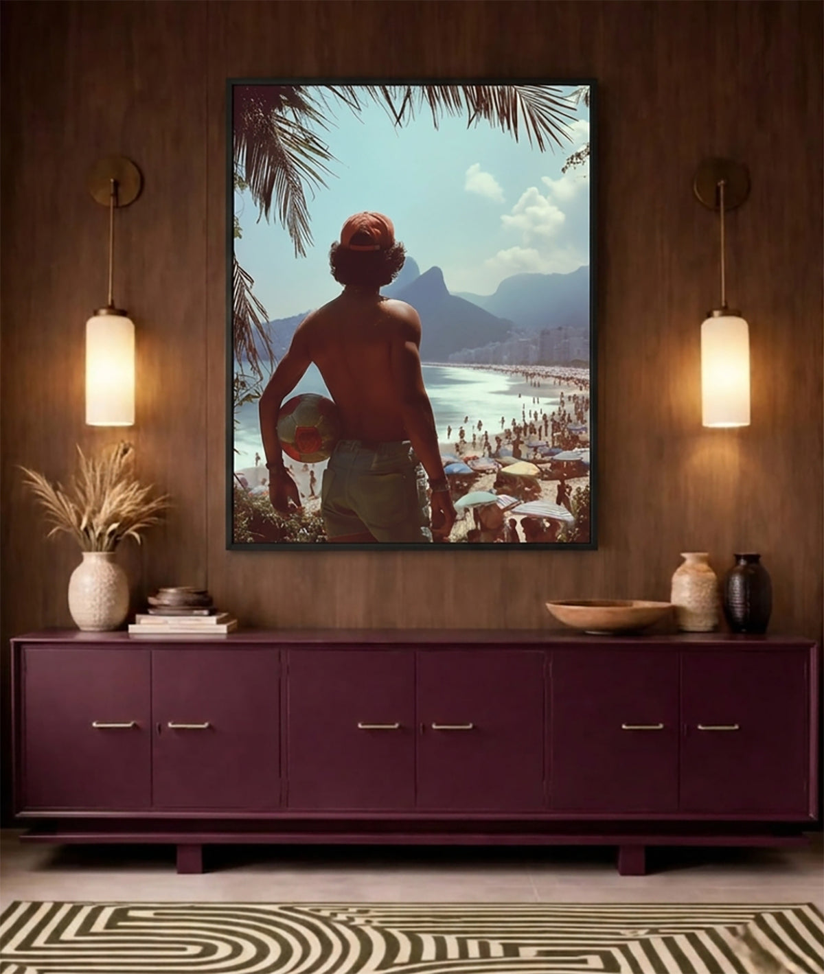 A framed art print depicting a shirtless man holding a beach ball on a beach, displayed on a dark wood wall above a purple sideboard with decorative items and two glowing wall lamps.