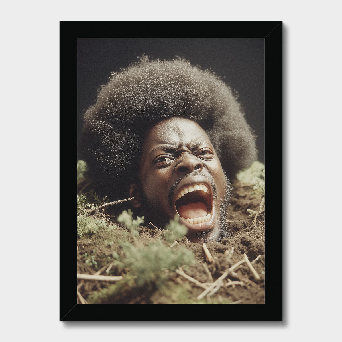 A framed photographic print showing a Black man with a large afro screaming from emerging from dirt and grass, set against a dark background. The print is enclosed in a simple black frame and displayed against a light gray wall.