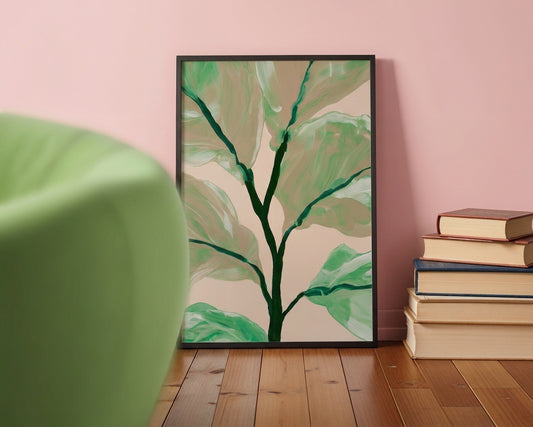 A framed botanical art print featuring a stylized tree with green leaves on a beige background, leaning against a pink wall on a wooden floor next to a stack of books and a green chair.