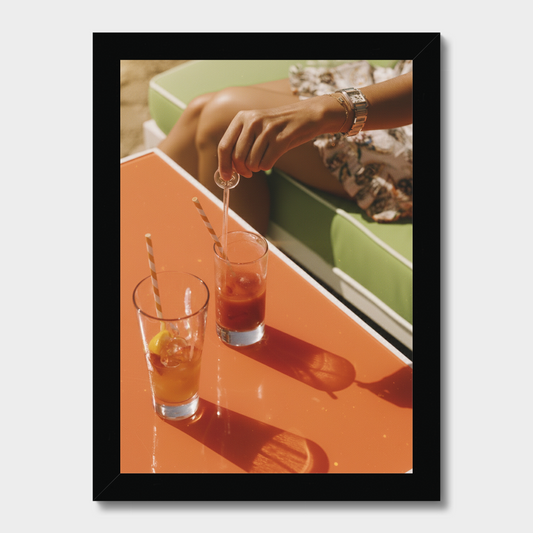 Person pouring a drink into a glass on a table with a blurred background