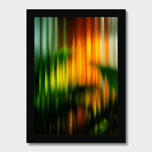 A framed abstract art print featuring vertical streaks of green, yellow, orange, and red, presented in a black frame against a light gray background.