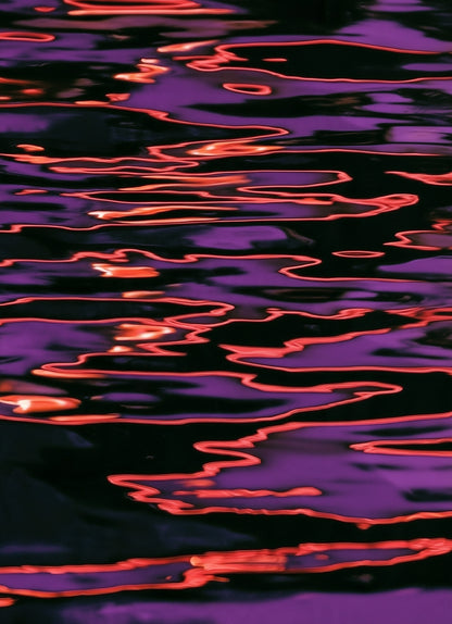 Abstract close-up of rippling water with purple reflections and bright orange-red light streaks on a dark surface.