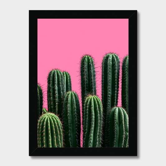 A framed art print featuring green cacti against a vibrant pink background, enclosed in a simple black frame.