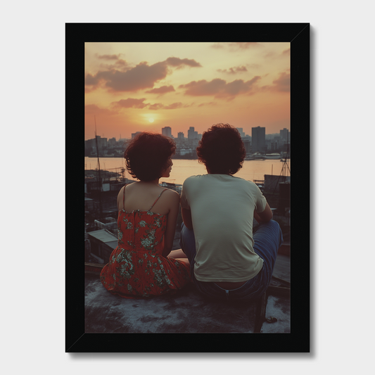 Two people sitting together on a rooftop at sunset with a city skyline in the background.