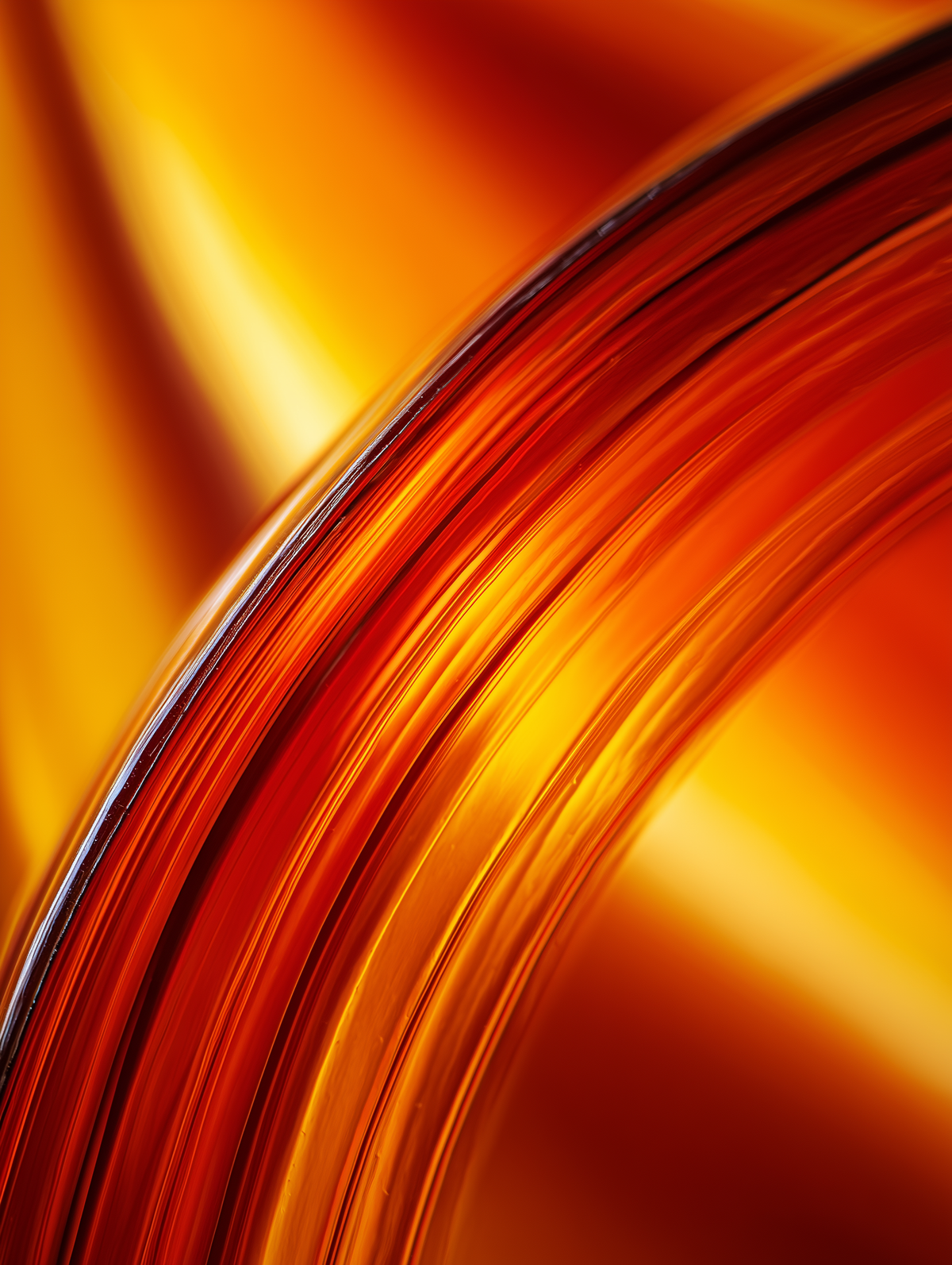 Abstract close-up of glossy curved ribbed material in warm orange, amber, and yellow tones with a reflective finish.