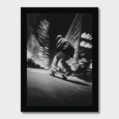 A framed black and white photographic print of a person skateboarding in a city at night, shown against a light gray background.
