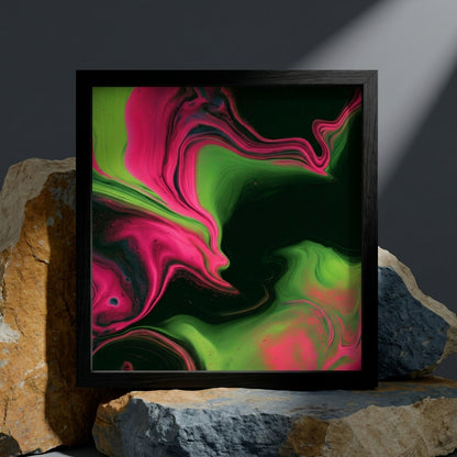 A square framed abstract art print featuring vibrant neon pink and lime green fluid swirls on a dark background, styled leaning against rustic rocks.