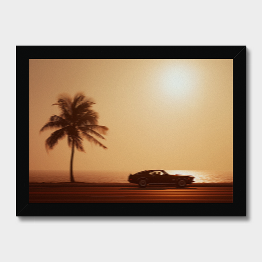 Silhouette of a car and palm tree against a sunset sky