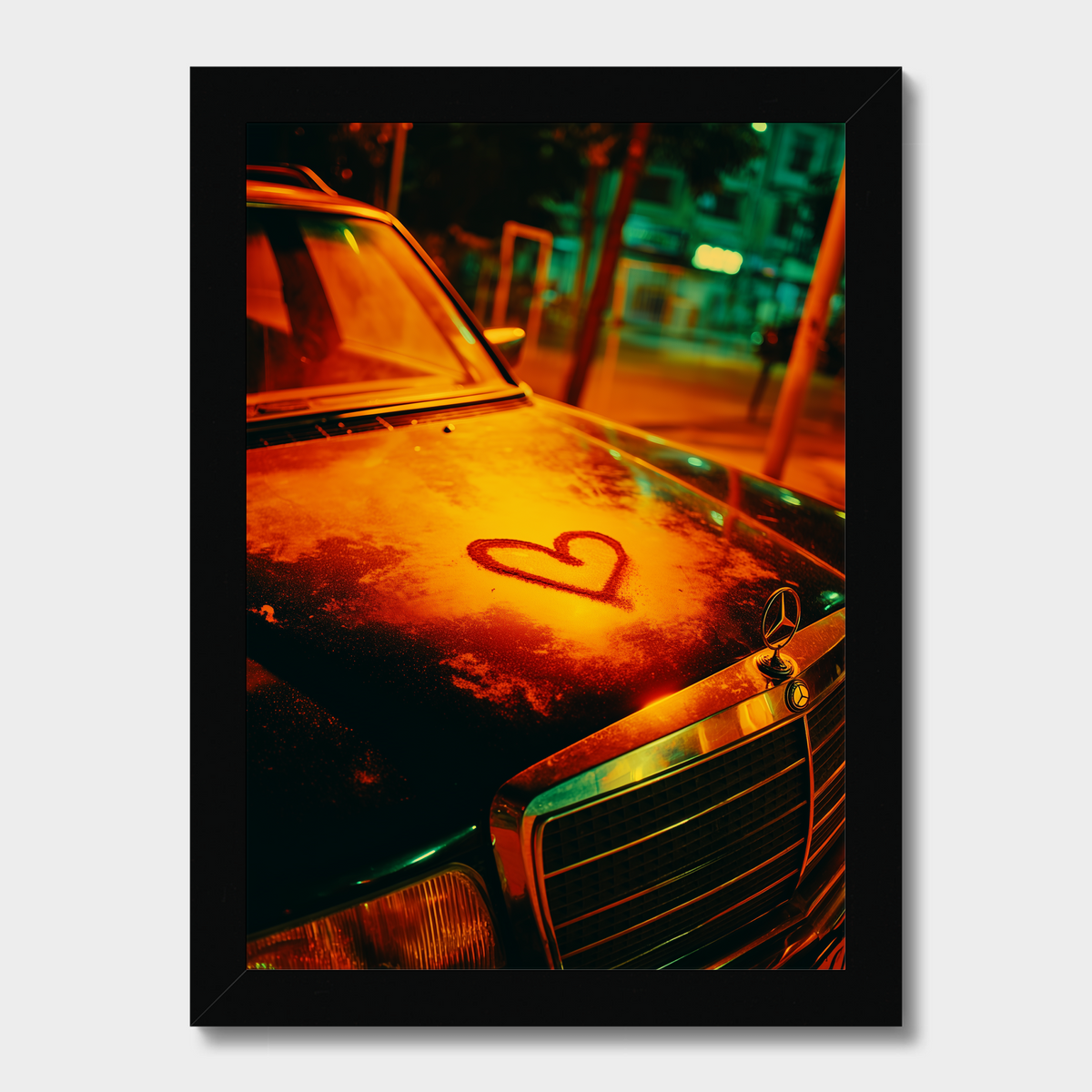 A framed vertical art print depicting a vintage Mercedes-Benz car on a city street at night, illuminated by warm orange streetlights with a red heart drawn on the hood. The print is housed in a simple black frame and shown against a light gray background.